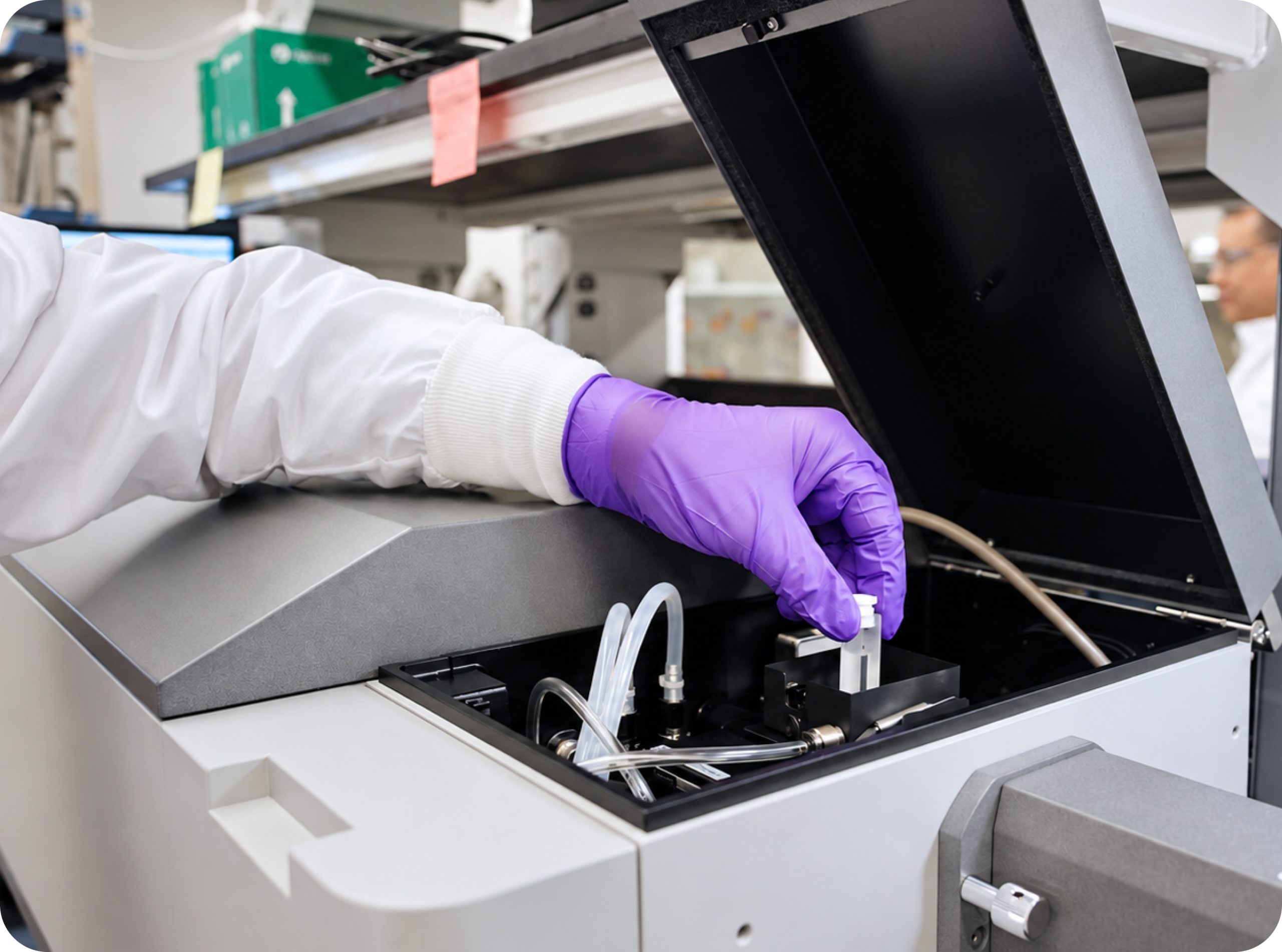 A gloved technician loading a sample vial into laboratory testing equipment