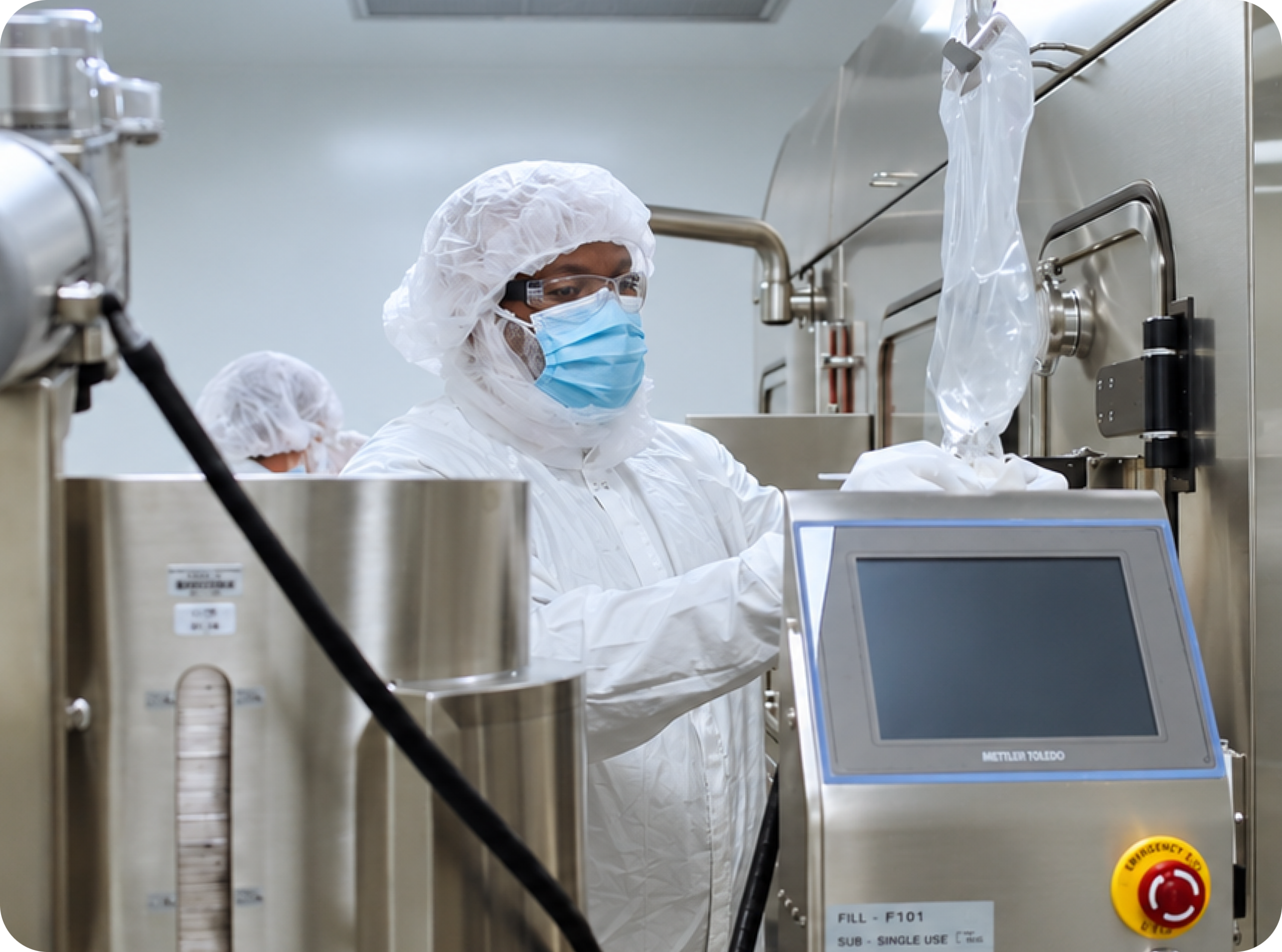 A cleanroom technician operating drug product manufacturing equipment